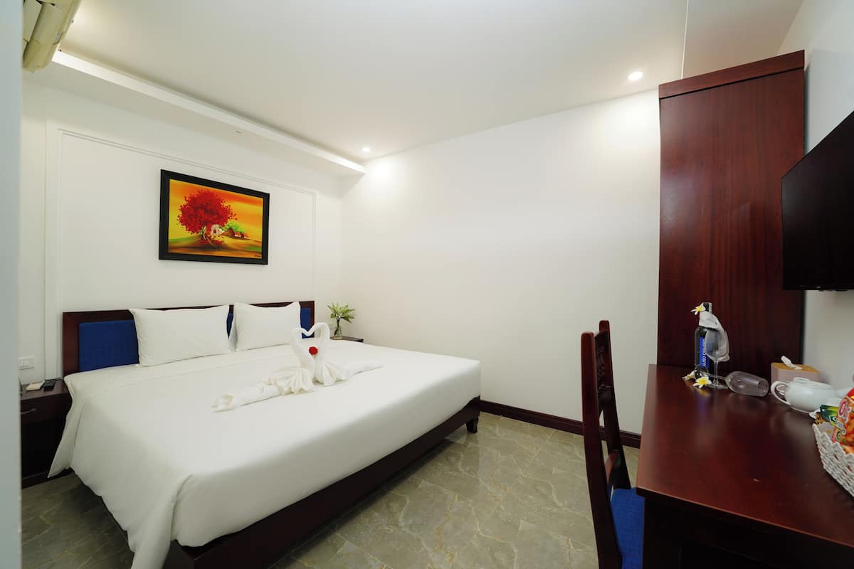 Une chambre d’hôtel avec un lit, un bureau, une chaise, une télévision et un tableau au mur.