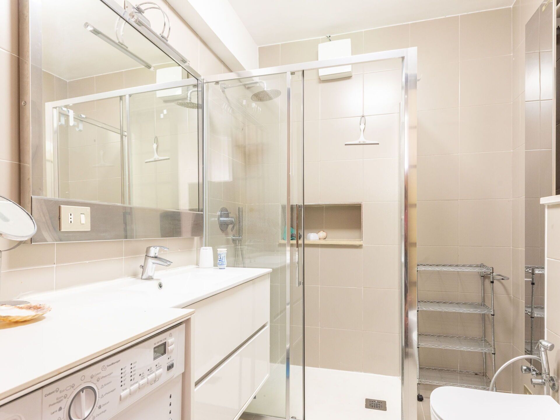 A modern bathroom with a glass-enclosed shower, a white sink, and a large mirror.