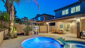 A backyard with a hot tub, outdoor furniture, and a patio area.