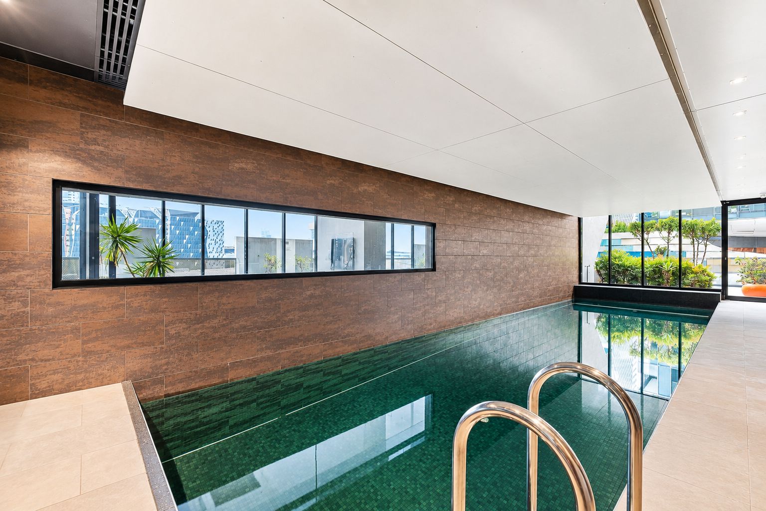 A modern indoor swimming pool with a clear view of the cityscape through large windows.