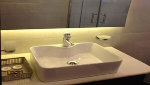 Une salle de bain avec un lavabo blanc, un miroir et des placards.