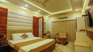 Une chambre d’hôtel moderne avec un grand lit, un ventilateur de plafond, un petit bureau, une chaise et une salle de bain.