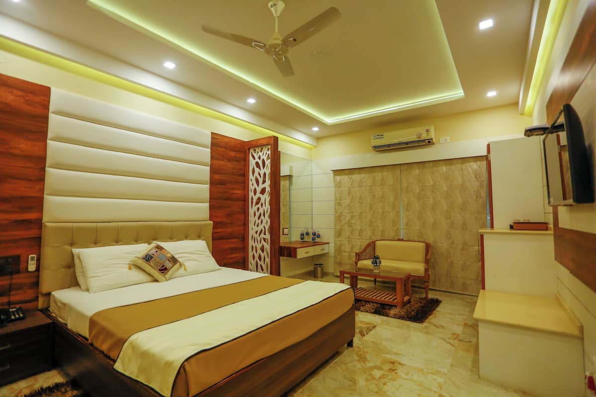 A modern hotel room with a large bed, a ceiling fan, a small desk, a chair, and a bathroom.