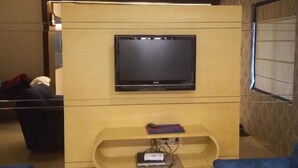 Un salon avec un téléviseur à écran plat fixé à un meuble de rangement en bois.