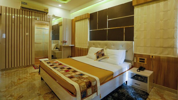 Une chambre d’hôtel moderne avec un grand lit, une table de chevet, une commode, un miroir et une armoire.