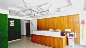 Un área de recepción con un mostrador de madera, un ventilador de techo y un extintor en la pared.