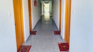 Un largo y estrecho pasillo con puertas de madera a ambos lados y un extintor de incendios sujeto a la pared.