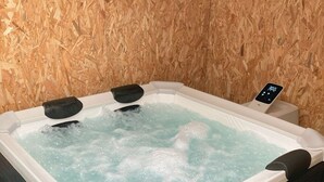 A hot tub with a digital control panel, surrounded by artificial grass and a wooden wall. - Cottage for 4 to 6 persons + private jacuzzi (Péault)