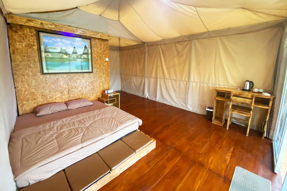 Una habitación con carpa, una cama, un escritorio y una silla.