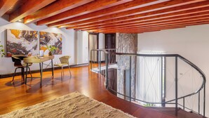 Ein modernes Interieur mit Holzboden, einem Essbereich mit Tisch und Stühlen sowie einem Glasgeländer mit Blick auf eine Steinwand.