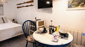 Ein Zimmer mit einem Bett, einem Esstisch mit Frühstücksangeboten, einem Fernseher an der Wand und einem Gemälde.