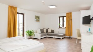 A modern hotel room with a bed, a sofa, a desk, and a TV. - Henrys Sleeping Buttenwiesen (Buttenwiesen)