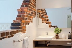 A bathroom with a white sink, a mirror, a towel rack, and a potted plant.