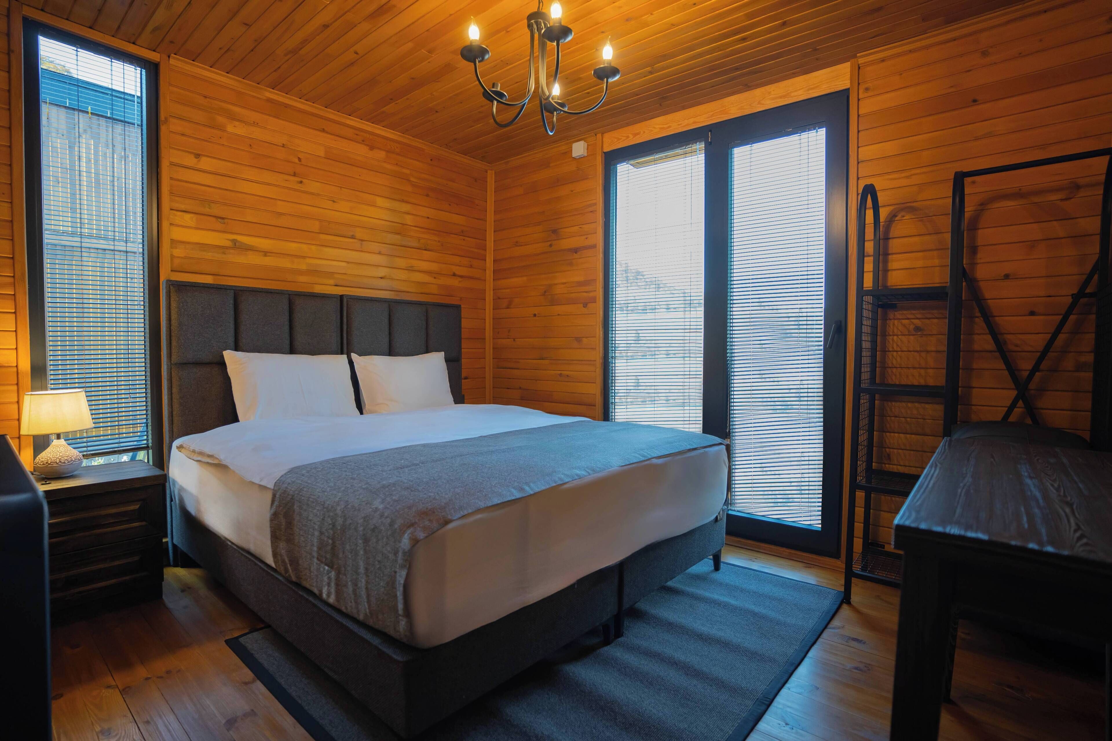 Un dormitorio con paneles de madera, una cama grande, una mesita de noche, un escritorio y una silla.