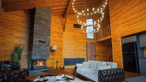 Una sala de estar acogedora con chimenea de piedra, mobiliario de cuero y techo de madera.