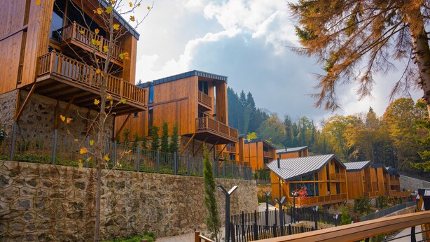 Un edificio de estilo cabaña de madera con balcones, paredes de piedra y un camino de piedra.