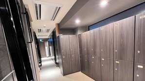 A corridor with lockers, a tiled floor, and recessed lighting. - Capsulehotel Suzumoriya (Tokyo)