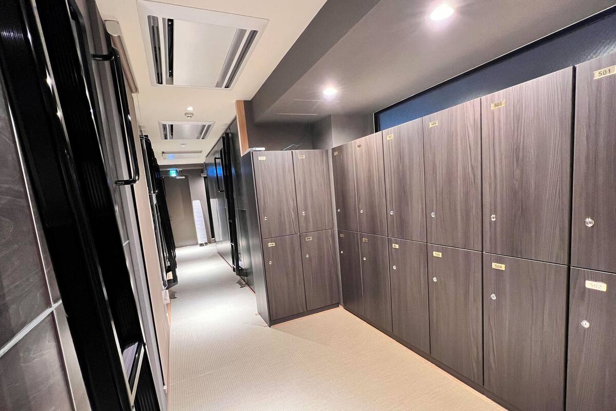 A corridor with lockers, a tiled floor, and recessed lighting.