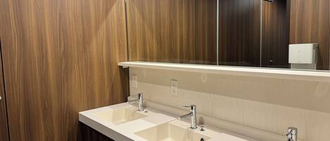 A modern bathroom with wooden paneling, a large mirror, and a double sink with chrome fixtures.