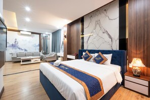 Moderni hotellihuone, jossa on suuri sänky, sohva, sohvapöytä ja marmorikuviolla koristeltu seinä.