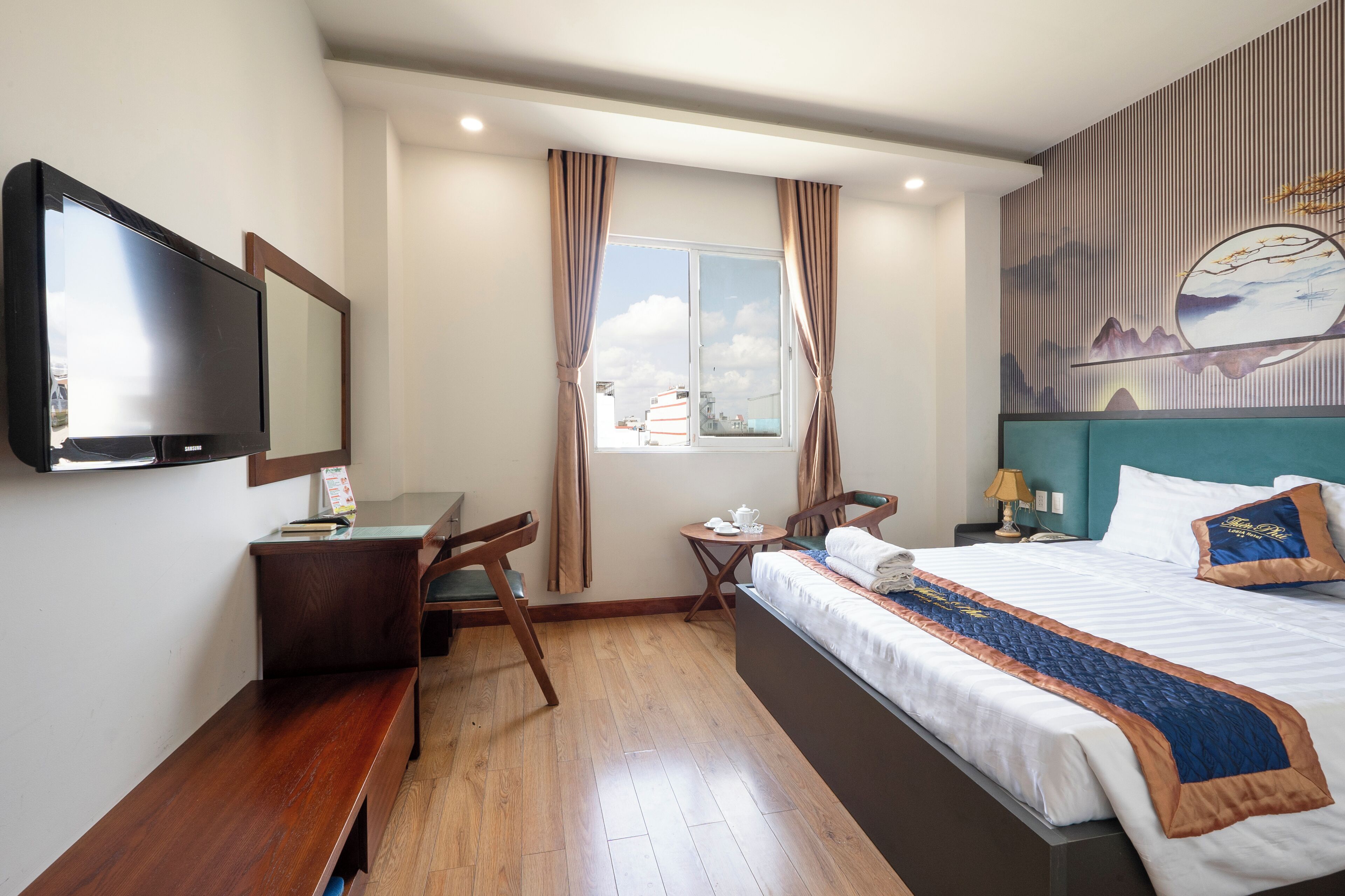 Een hotelkamer met een bed, een bureau, een stoel, een televisie en een raam met gordijnen.