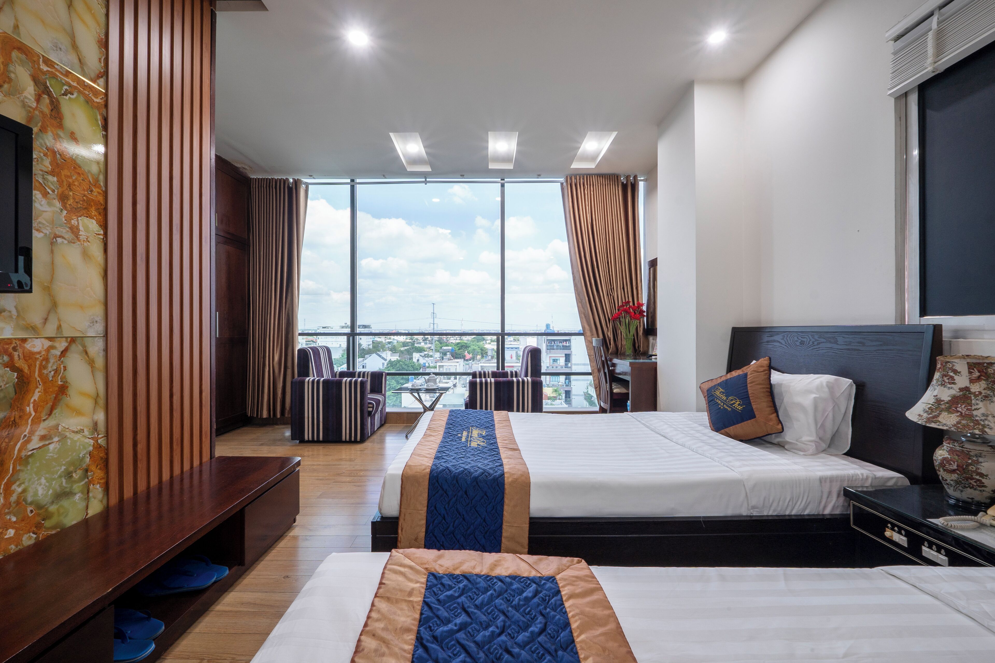 Una habitación de hotel con un ventanal grande, una cama, un escritorio y un espacio para sentarse.
