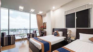 A hotel room with two beds, a desk, and a view of the city. - THIÊN PHÚ LOGIA HOTEL (Ho Chi Minh City)