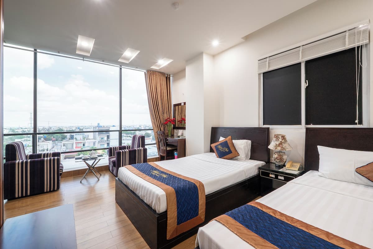 Une chambre d’hôtel avec deux lits, un bureau et une vue sur la ville.