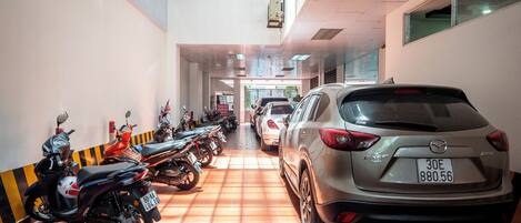 Un parking souterrain où sont stationnés de nombreux véhicules, notamment des voitures et des motos, de manière ordonnée.