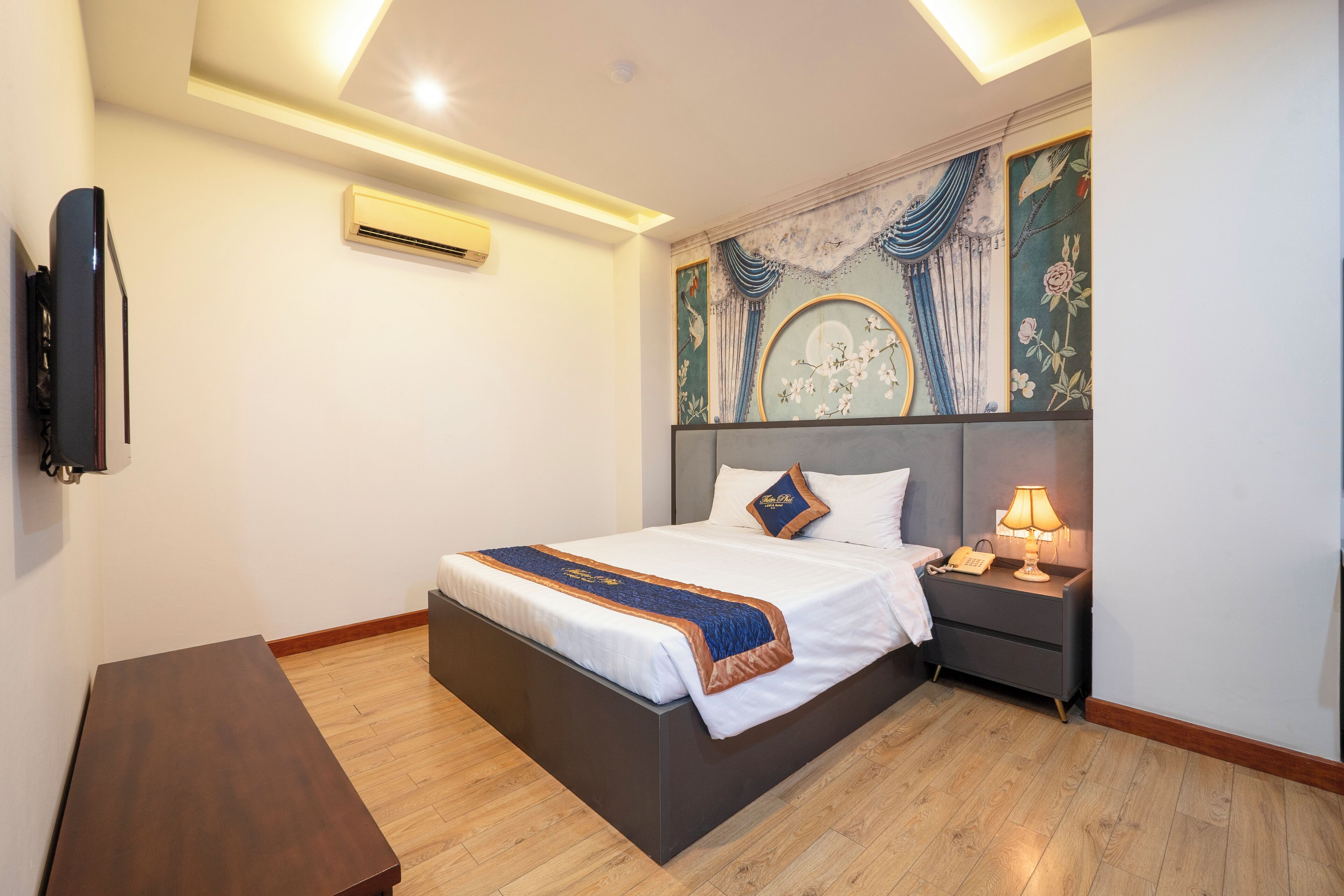 Ein Hotelzimmer mit Bett, Nachttisch, Lampe und Wanddekoration.