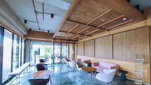 A spacious indoor area with a high ceiling, large windows, and a mix of seating arrangements including sofas and chairs.