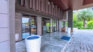 A modern hotel entrance with a covered walkway, large windows, and a patterned wall.