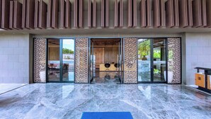 A modern building entrance with a marble floor, patterned glass doors, and a reception desk.