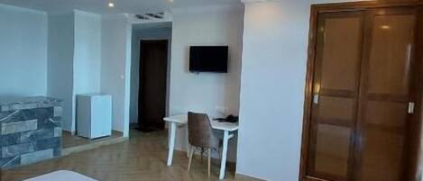 Habitación de hotel con dos camas, un escritorio con una silla, un televisor en la pared y un armario de madera.