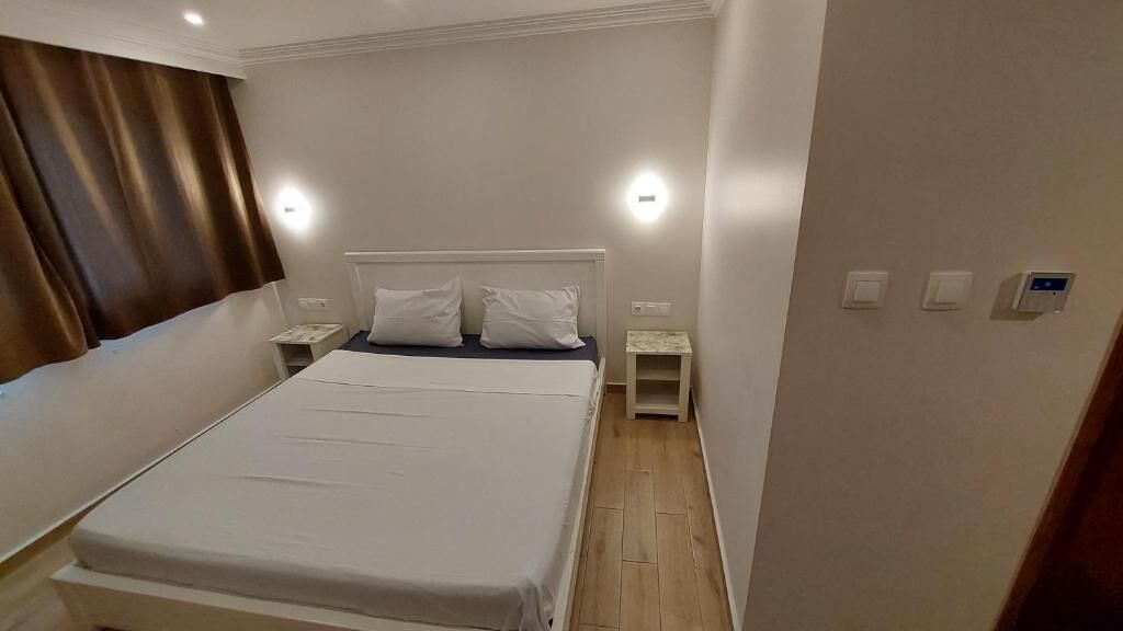 A hotel room with a bed, two bedside tables, and a nightstand.