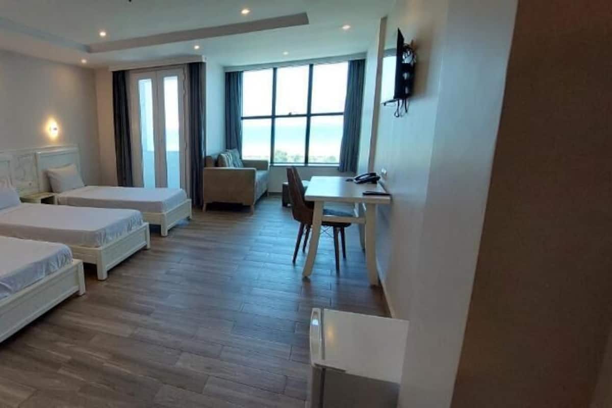 A hotel room with two single beds, a desk, and a chair.