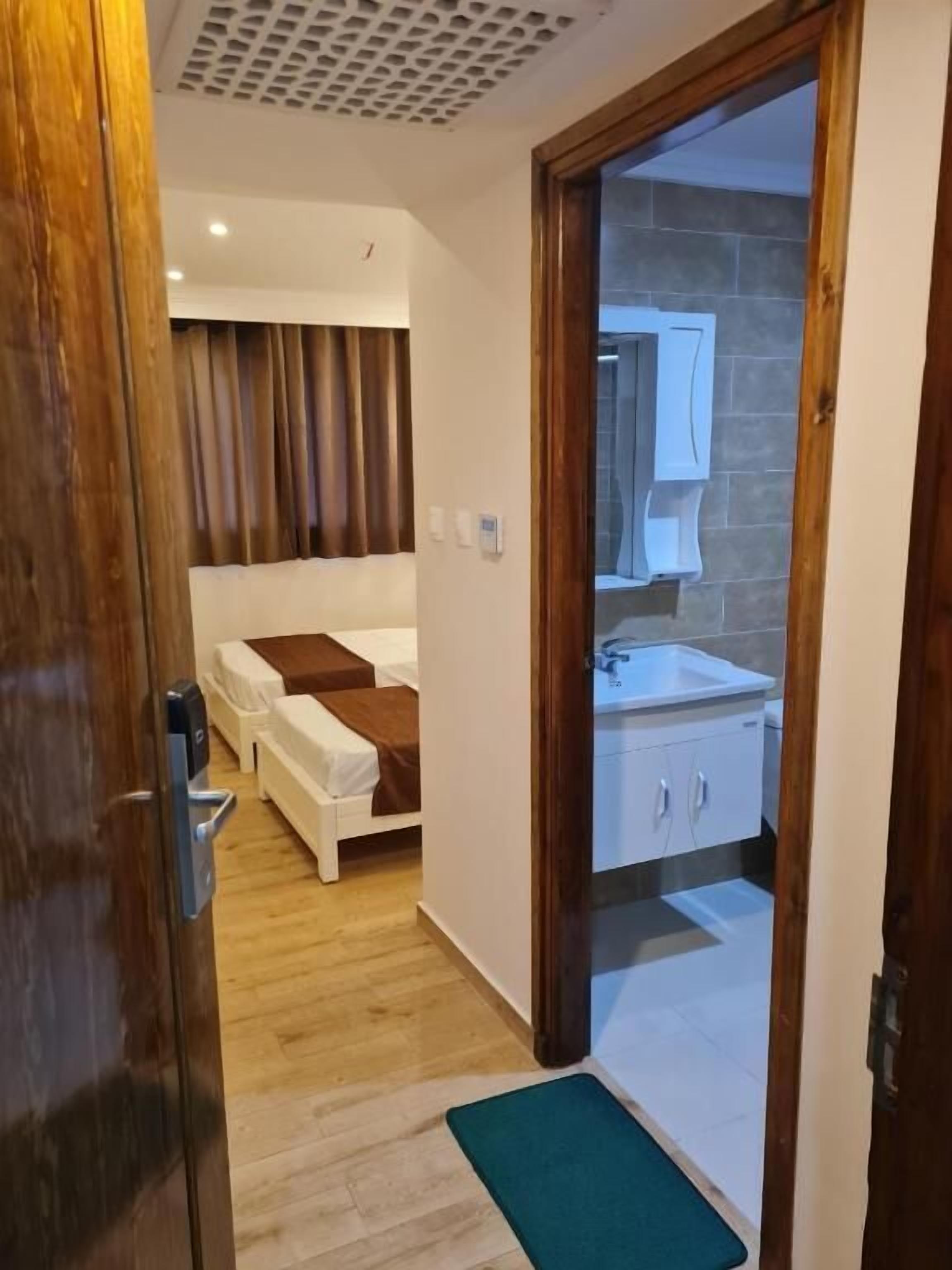 Een hotelkamer met een bed, een badkamer met een wastafel en kastjes, en een houten vloer.