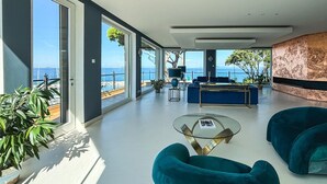 Un amplio salón con ventanas grandes, una mesa de billar y vistas al mar.