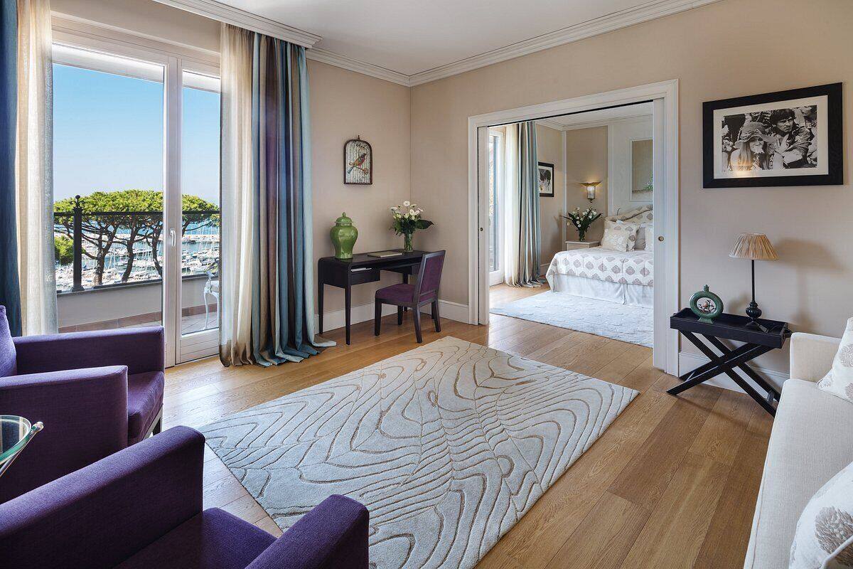 Habitación de hotel con balcón, escritorio, cama y vistas al mar.