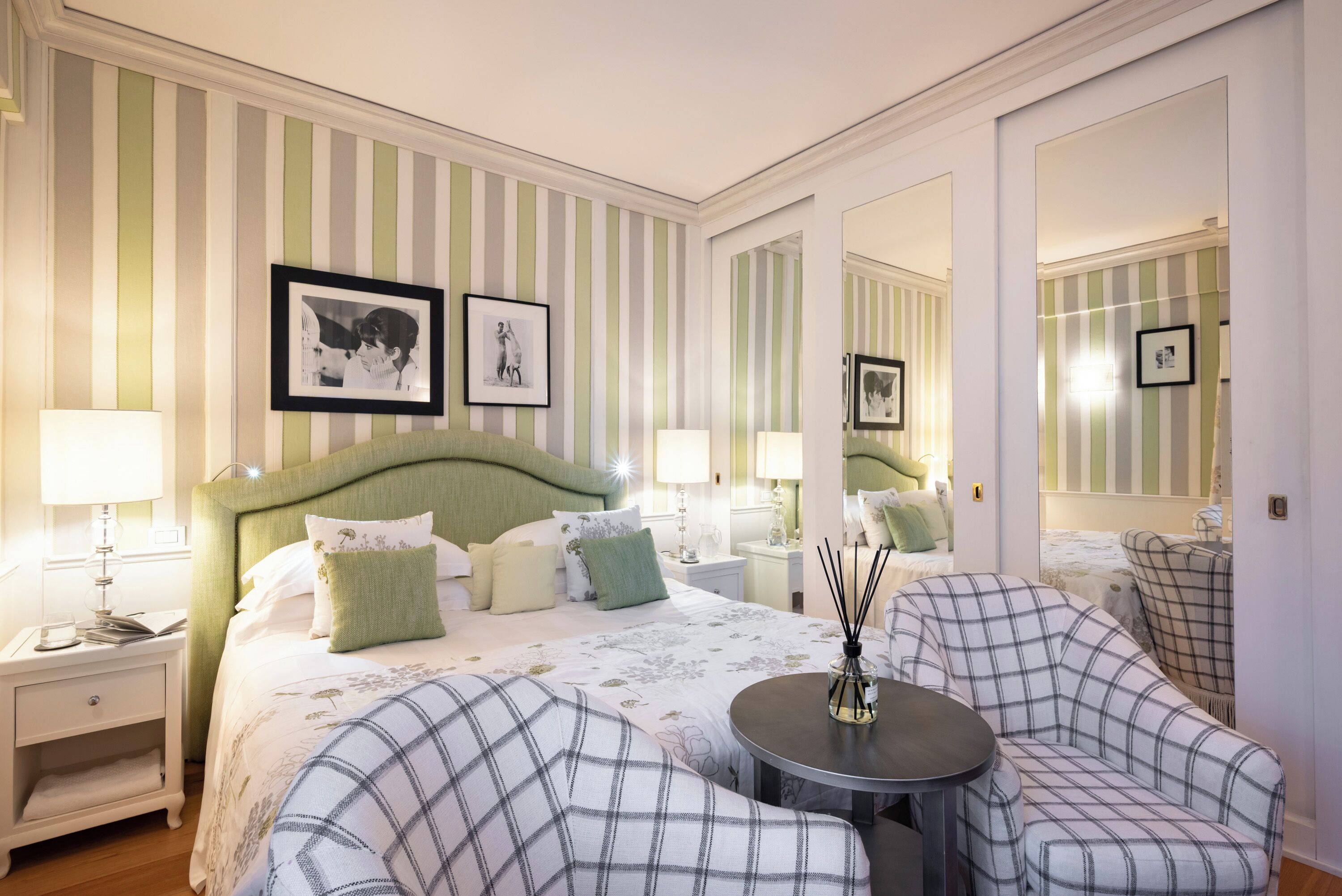 A hotel room with a bed, two nightstands, a round table, a sofa, and a mirror.
