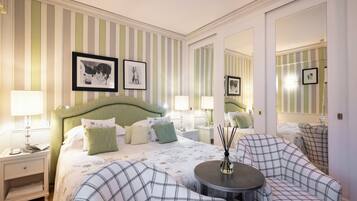 A hotel room with a bed, two nightstands, a round table, a sofa, and a mirror.