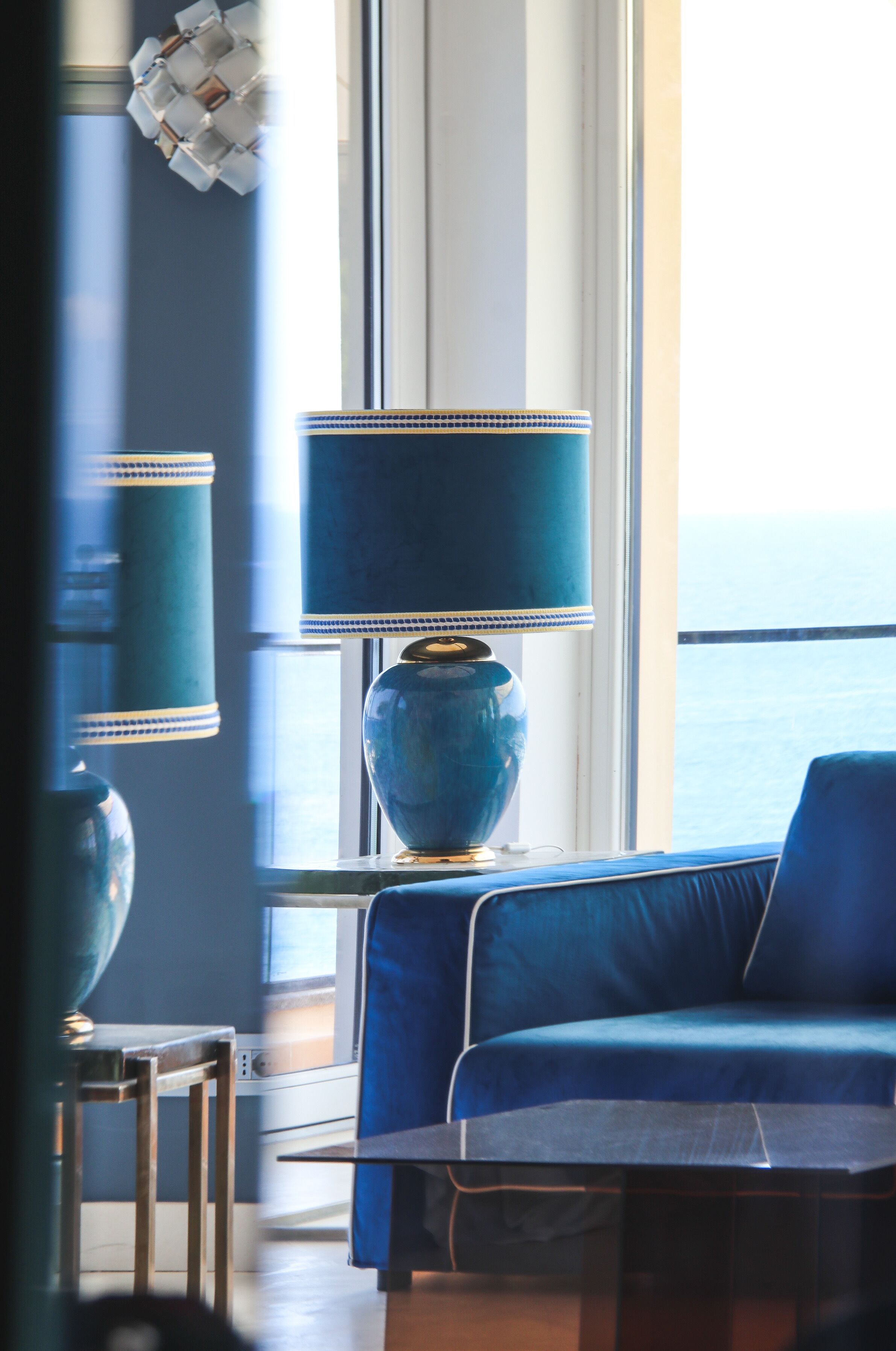 Ein Zimmer mit einem großen Fenster, einem blauen Sofa und einer blauen Lampe.