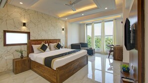 A modern bedroom with a large bed, a desk, and a television. - Hotel Emporio Grand (Ghaziabad)