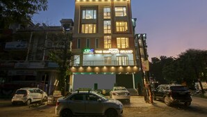 A hotel with multiple floors, a signboard for 'The Emporio Grand', and several parked cars in front. - Hotel Emporio Grand (Ghaziabad)