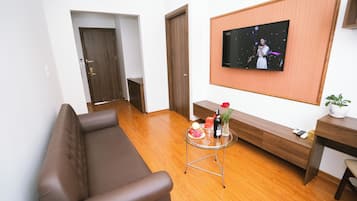 Suite Deluxe, vista città | Area soggiorno | TV a schermo piatto 32 pollici con canali via cavo