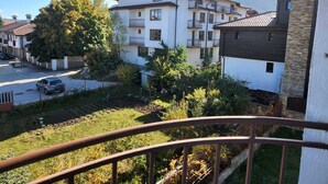 A residential area with multi-story buildings, a clear sky, and a mountain in the background. - Monfort A (Bansko)