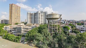 A high-rise building with multiple floors, surrounded by smaller buildings and trees.