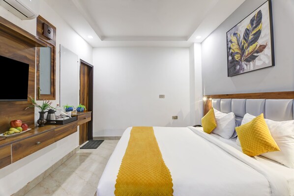 A hotel room with a bed, a TV, a wooden dresser, and a painting on the wall. - Hotel Status By SBG (Ghaziabad)