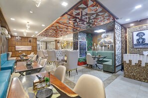 A modern hotel lobby with a variety of seating options, including sofas, chairs, and a dining area. - Hotel Status By SBG (Ghaziabad)