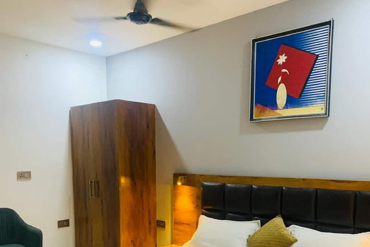 Un dormitorio con una cama grande, un armario de madera, un ventilador de techo y una obra de arte colgada en la pared.